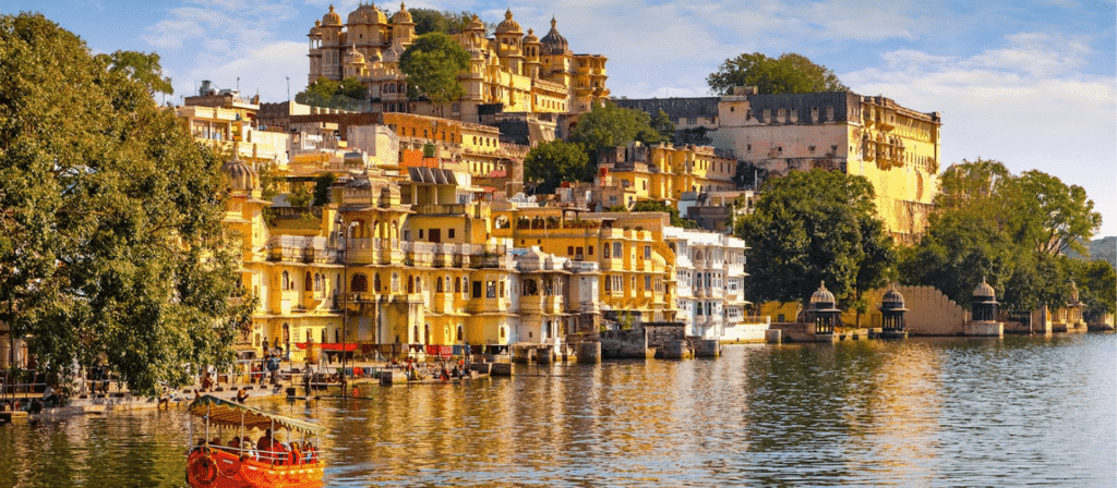 Panoramic view of Udaipur City Palace and ghats along Lake Pichola with a tourist boat